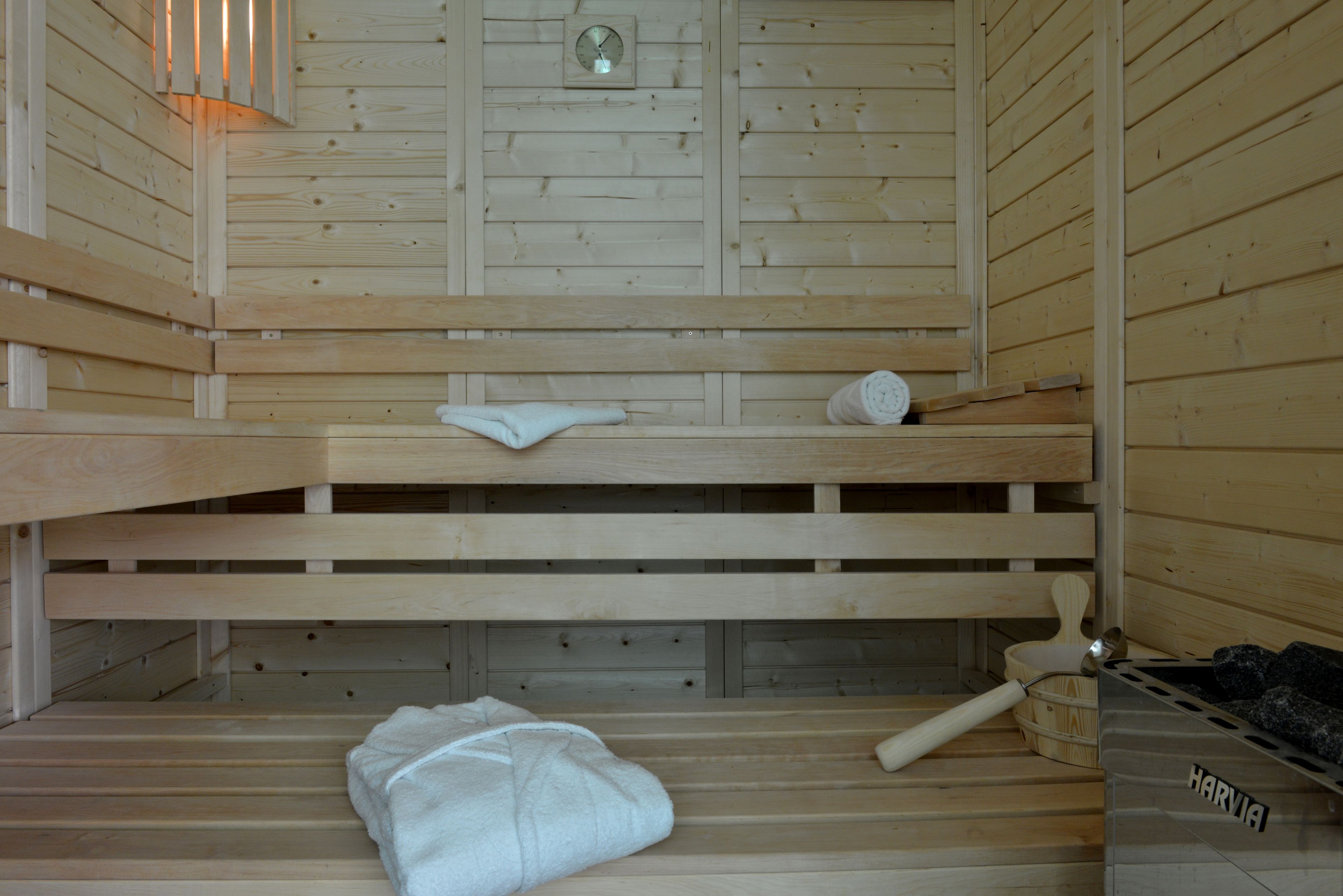A sauna with wooden benches, a towel, and a wooden bucket.