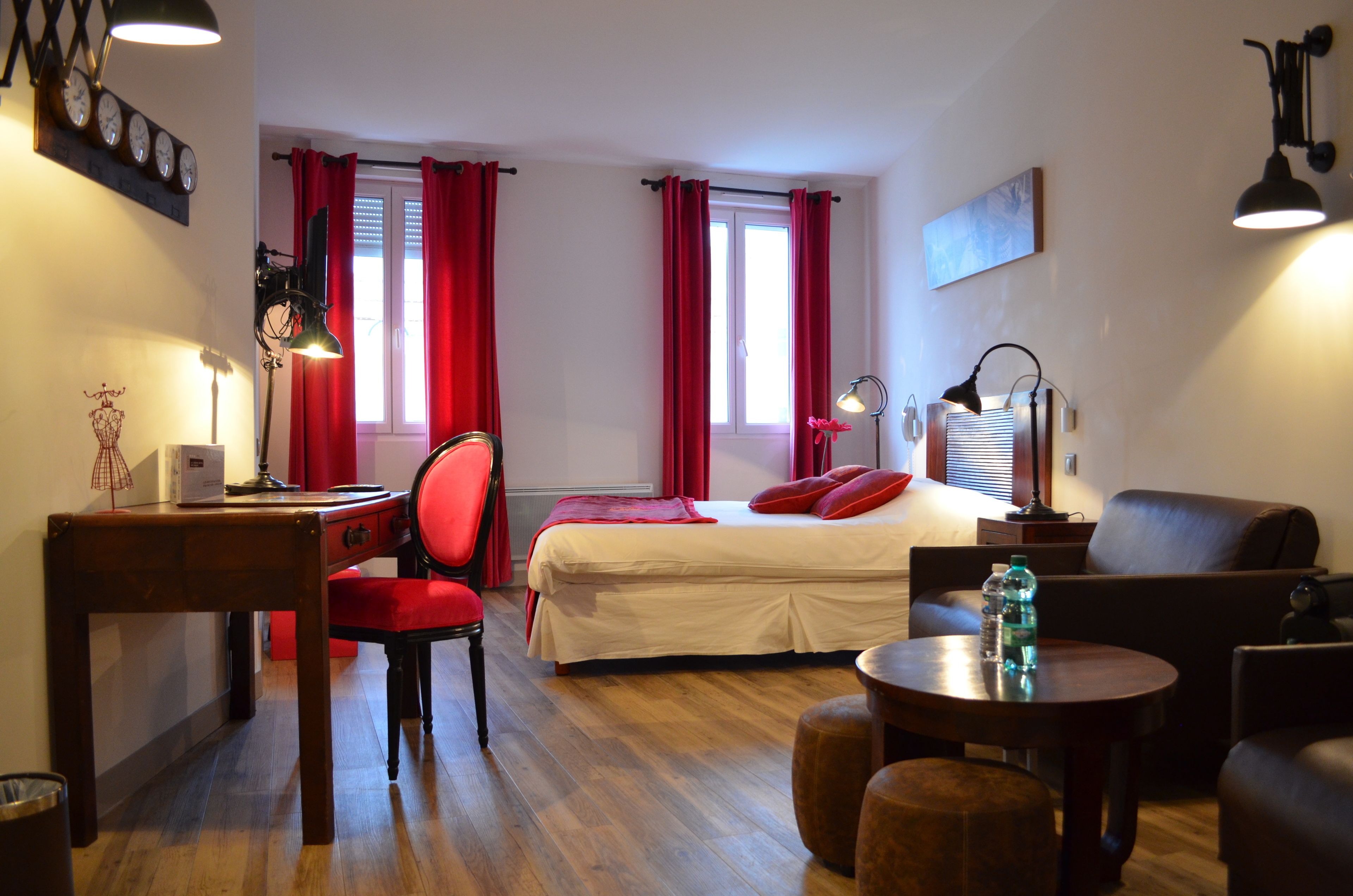 Una habitación de hotel con una cama, un escritorio, una silla, un sofá, una mesa y una lámpara.