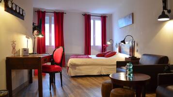 Una habitación de hotel con una cama, un escritorio, una silla, un sofá, una mesa y una lámpara.