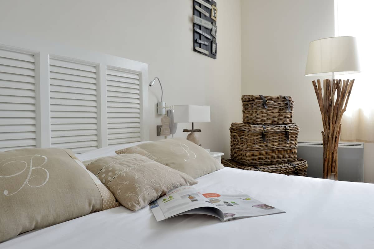 Un lit bien fait, avec des oreillers, un magazine et une lampe.