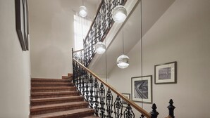 A staircase with wooden steps and black wrought iron railings, illuminated by hanging spherical lights. - Basilica (Budapest)