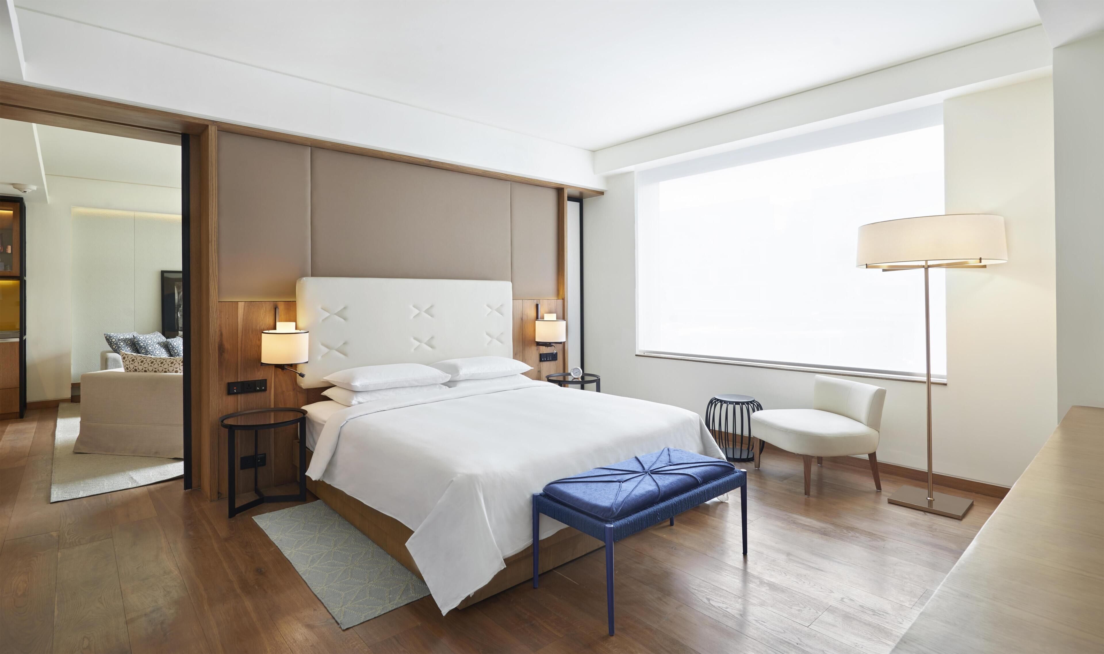 Une chambre d’hôtel moderne, dotée d’un grand lit, de tables de chevet, d’un bureau et d’une chaise.