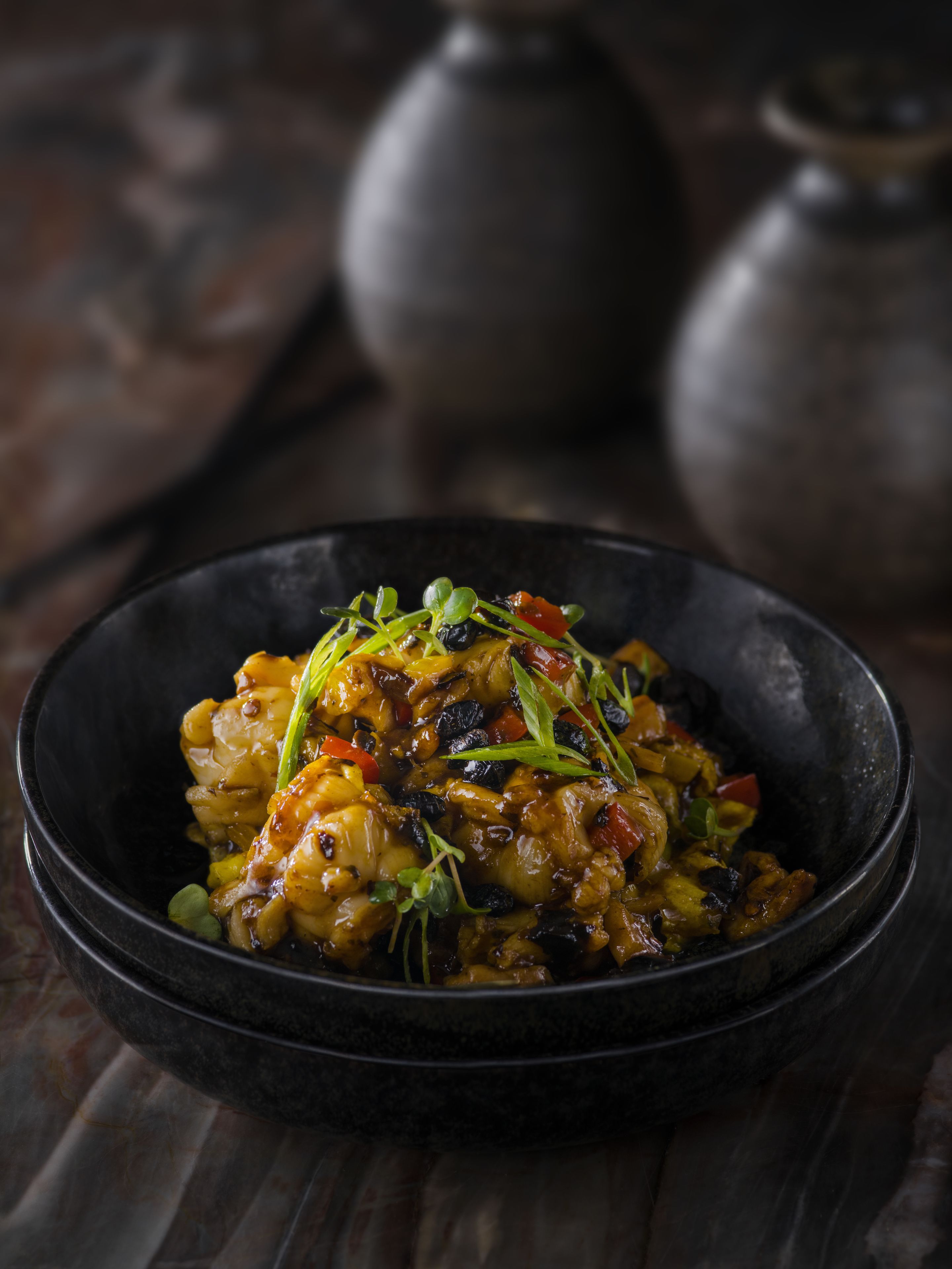 A bowl of food with various vegetables and garnishes.