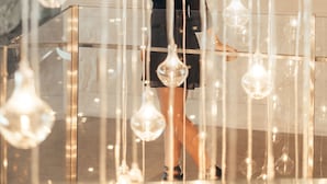 A woman standing in a modern lobby with hanging glass light fixtures. - Andaz Delhi, by Hyatt (New Delhi)