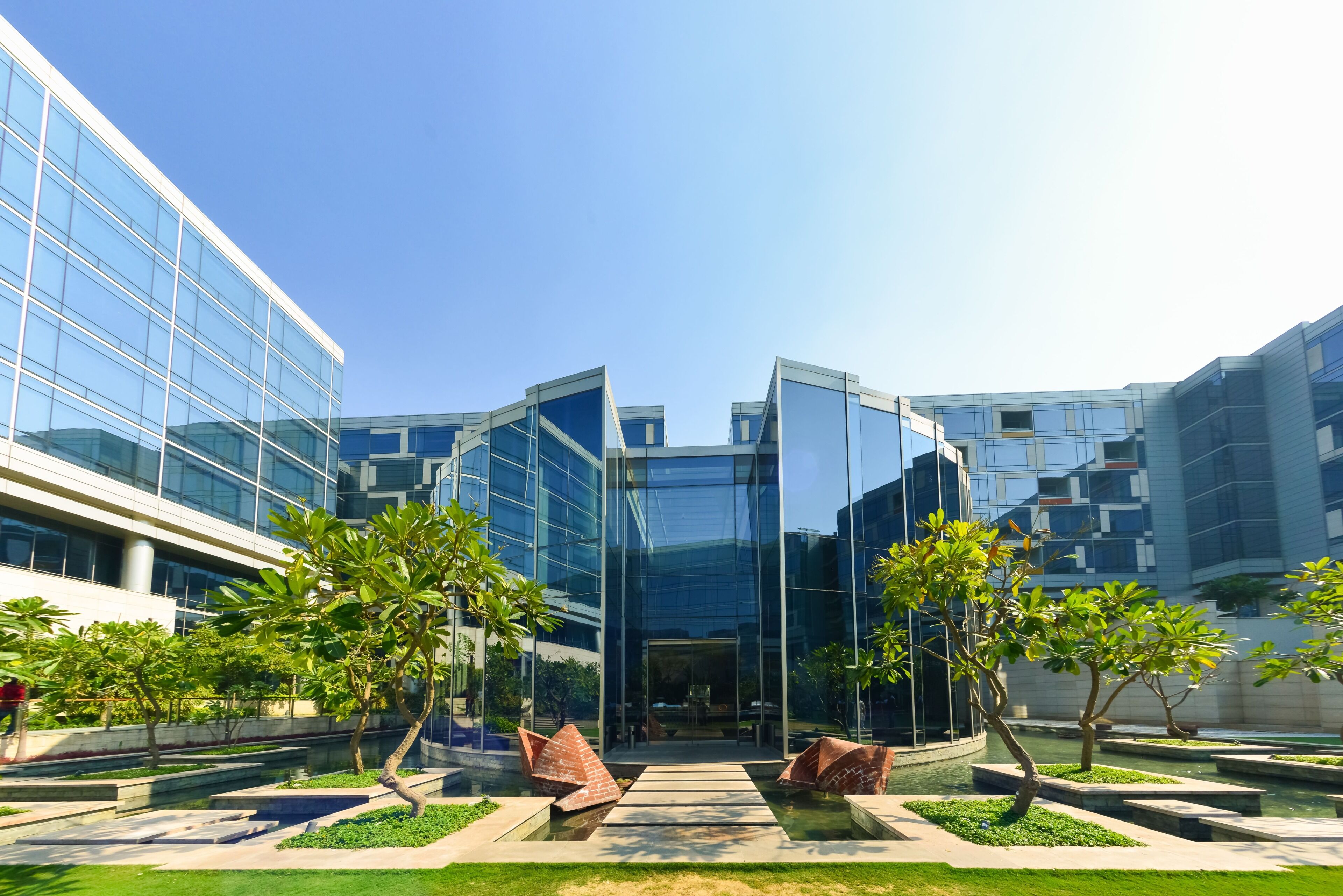 A modern building with glass facades and a courtyard with trees and a water feature.