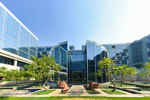 A modern building with glass facades and a courtyard with trees and a water feature.