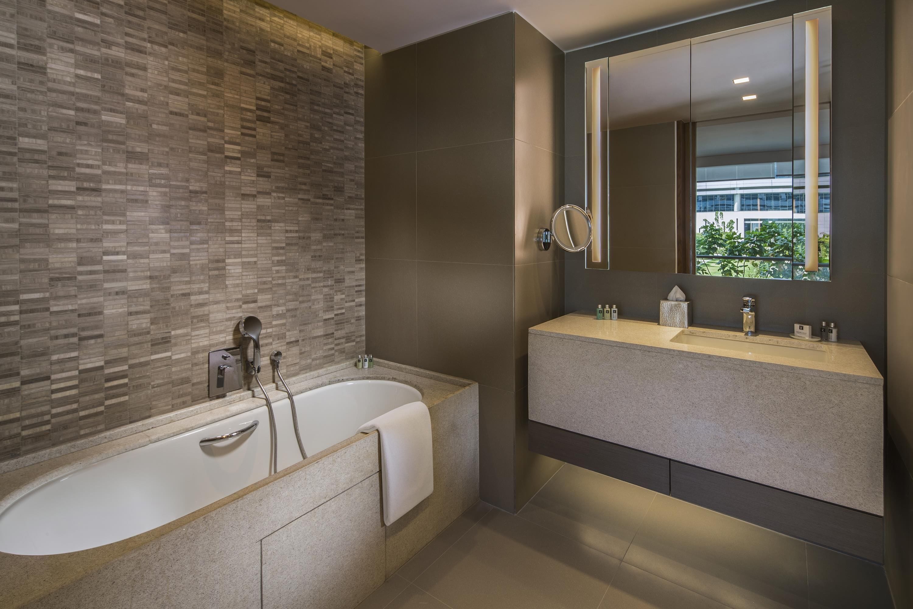 A modern bathroom with a freestanding bathtub, a large mirror, and a vanity with a sink.