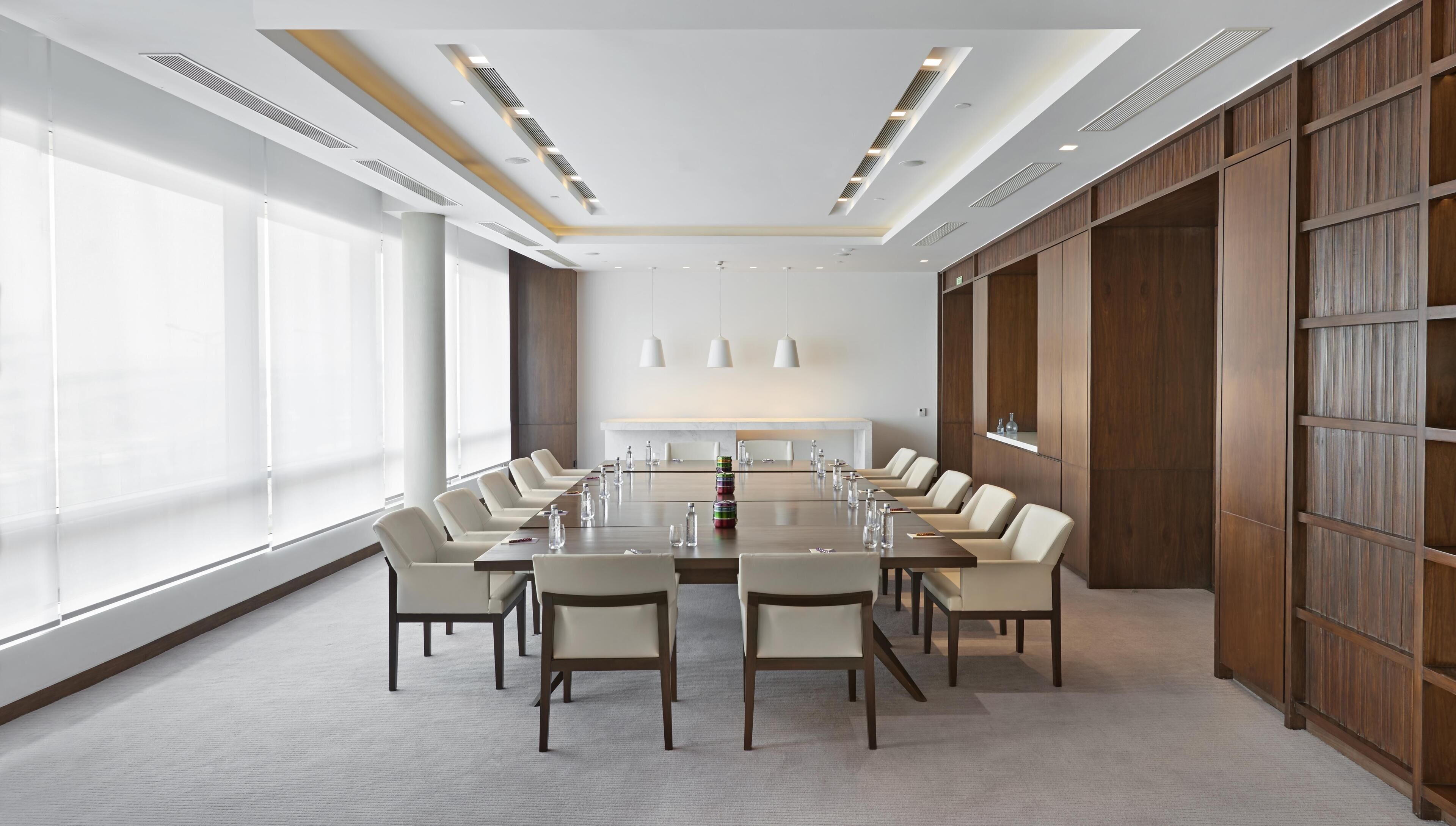 Une salle de conférence avec une longue table, des chaises et une grande fenêtre.