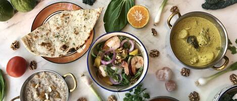 A variety of dishes including flatbread, a salad with shrimp, and several bowls of soup and rice.
