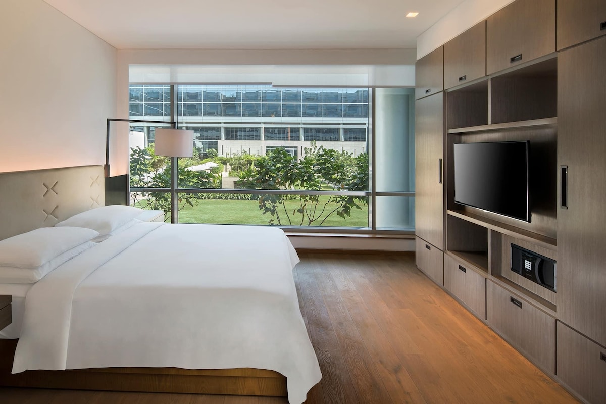 Een hotelkamer met een bed, een televisie en houten kasten.