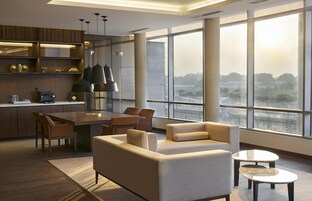 Un interior moderno con zona de comedor, sofá y ventanas amplias que ofrecen vistas.