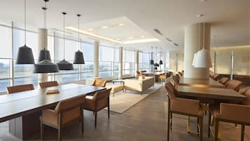 A modern hotel lobby with a large dining area, multiple seating options, and large windows offering a view.