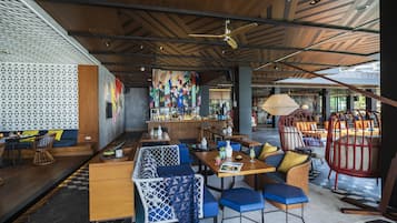 A modern restaurant with a bar area, seating arrangements, and a patterned ceiling.