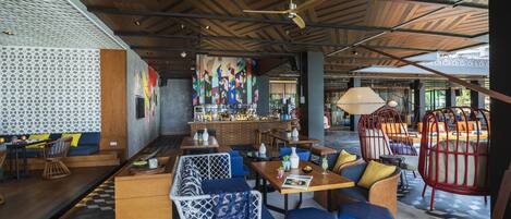 A modern restaurant with a bar area, seating arrangements, and a patterned ceiling.