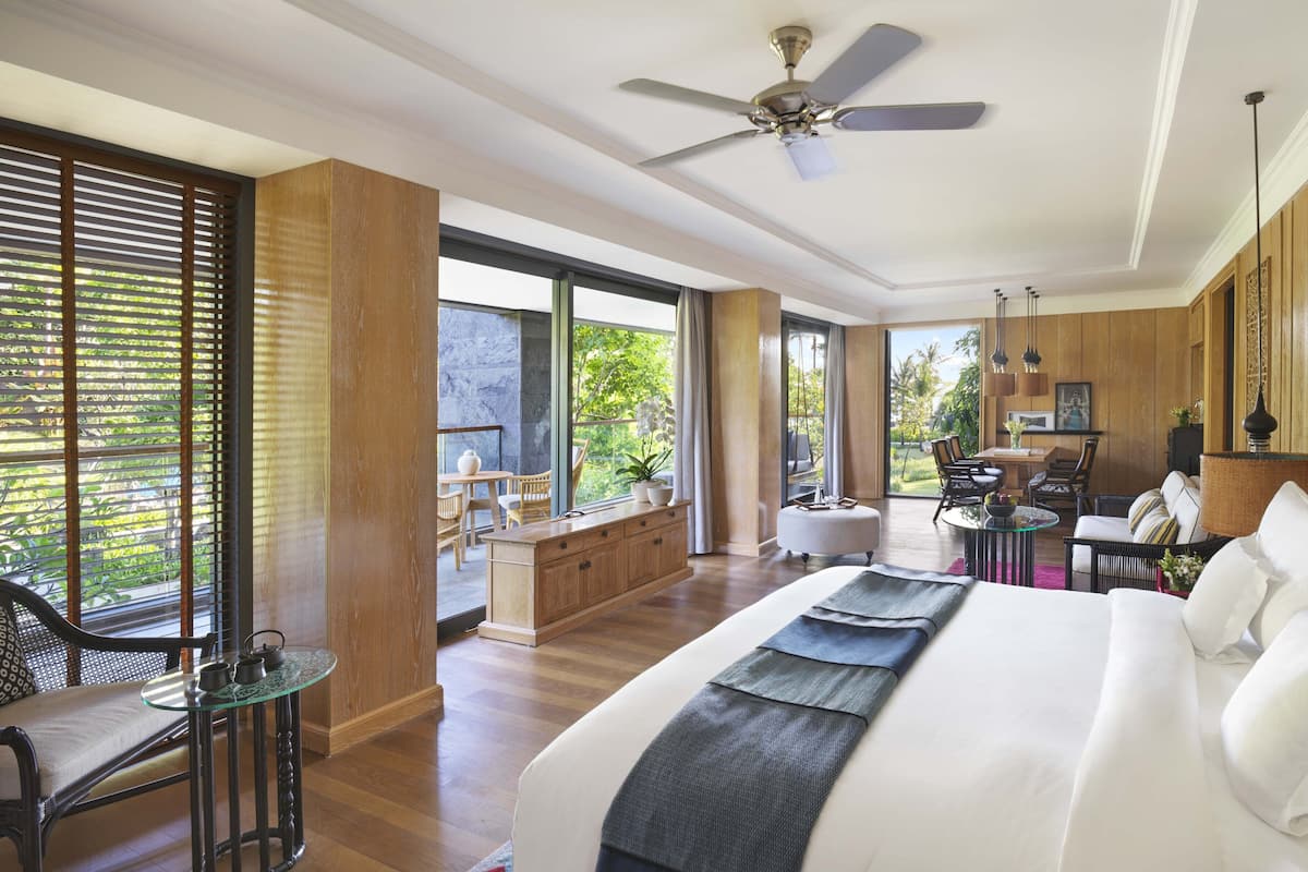 Ein geräumiges Schlafzimmer mit einem großen Bett, einem Deckenventilator und Blick ins Freie.