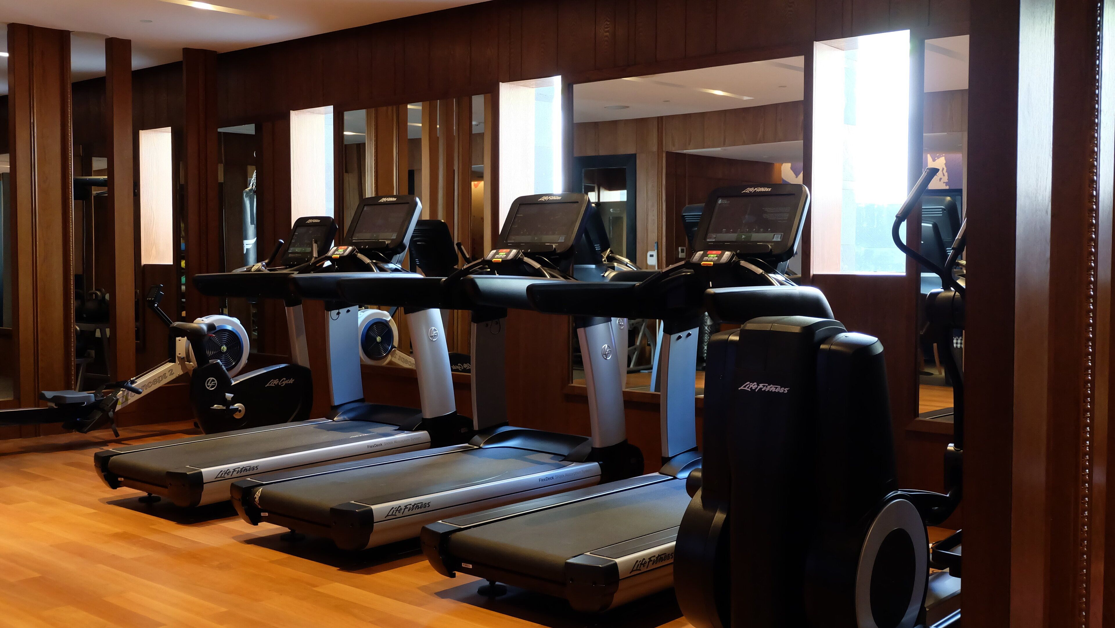 A gym with multiple treadmills, exercise bikes, and mirrors.