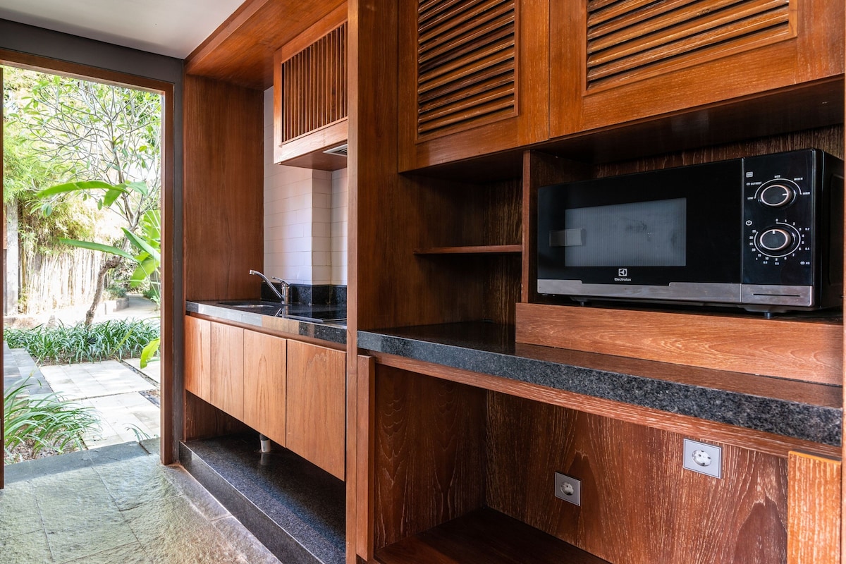 A modern kitchen with wooden cabinetry, a built-in microwave, and a sink.
