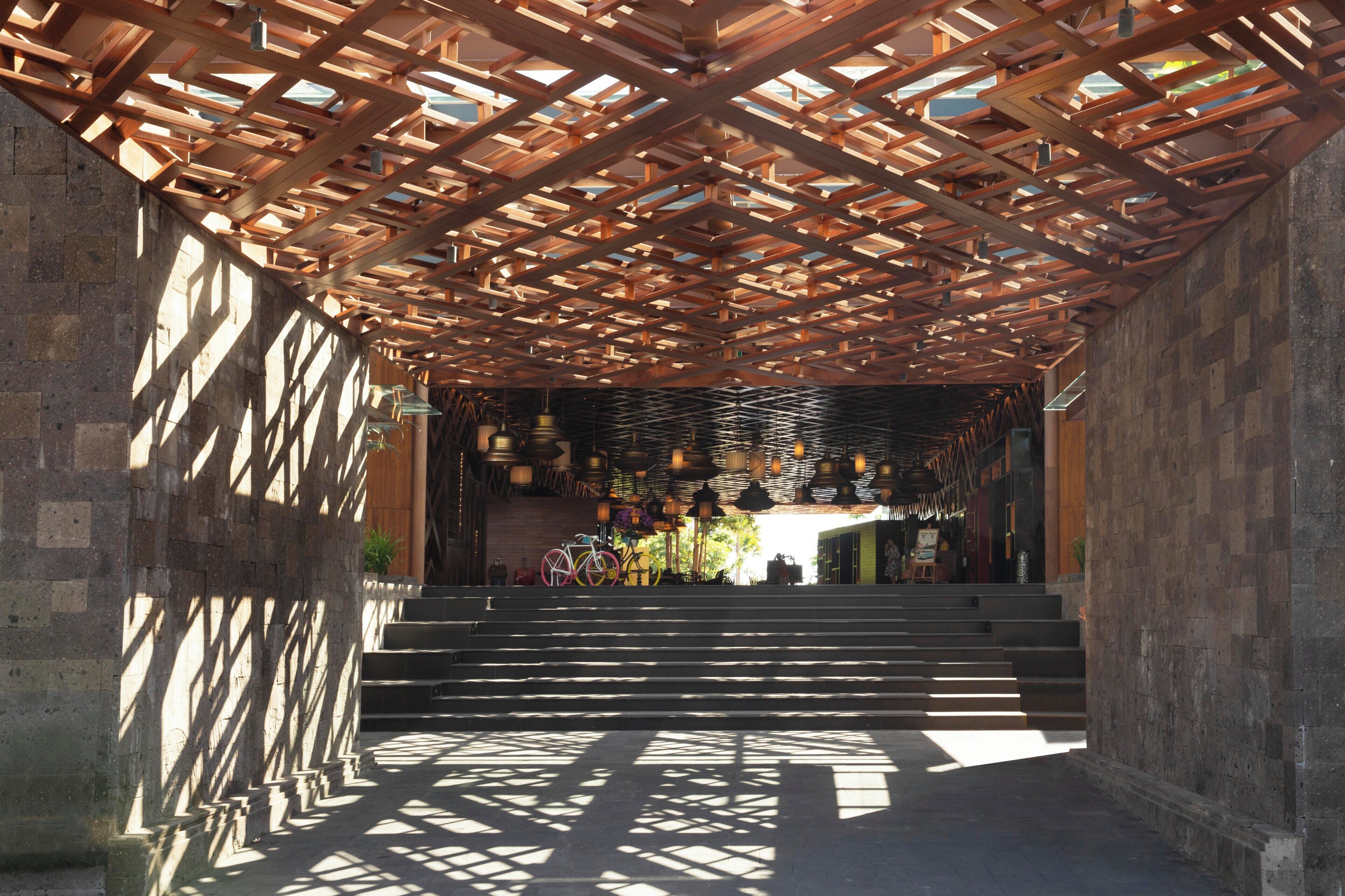 A covered outdoor area with a wooden ceiling structure, steps leading to a lower level, and hanging lights.