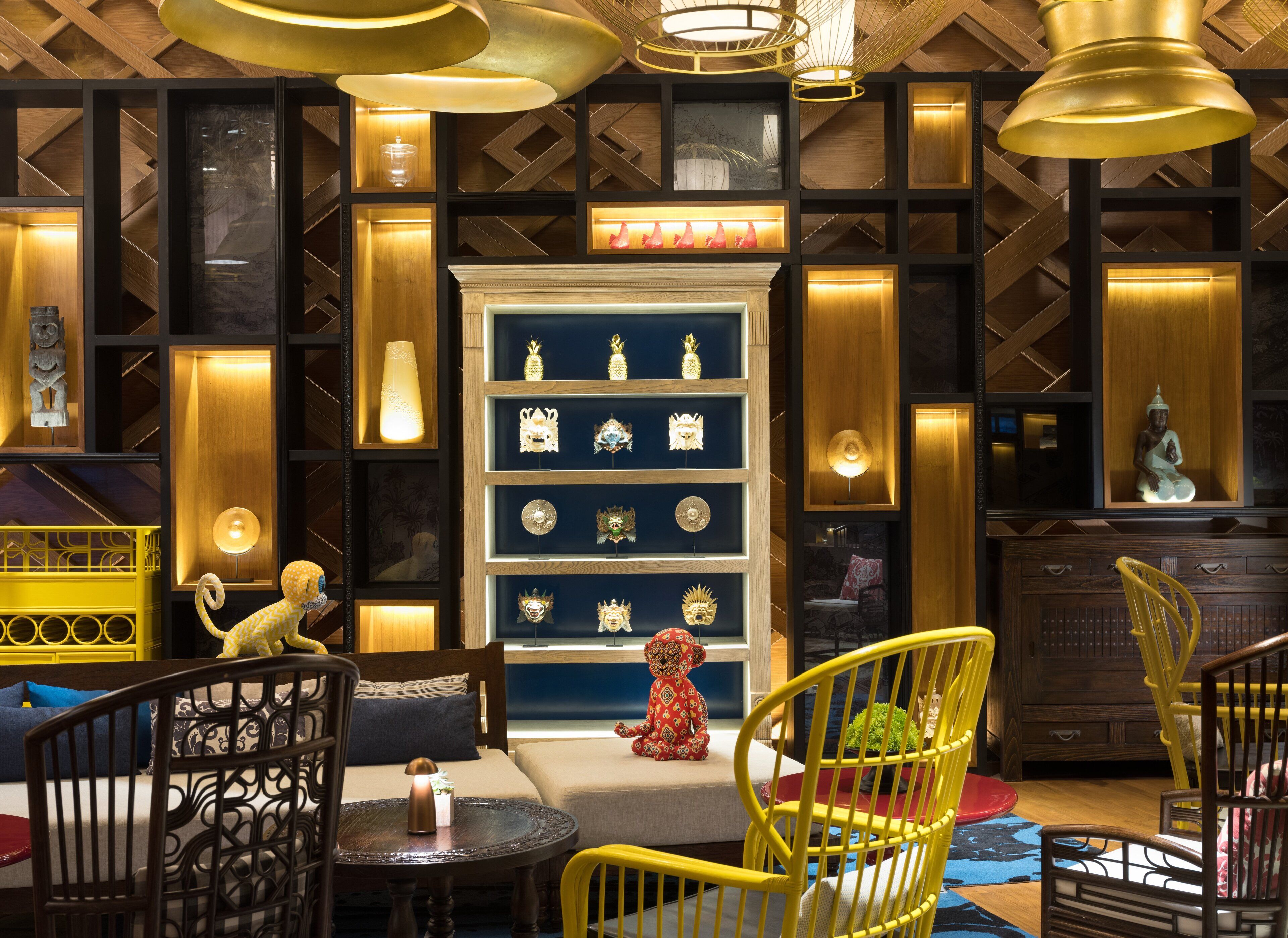 A room with a central fireplace, a bookshelf with decorative items, and yellow chairs.