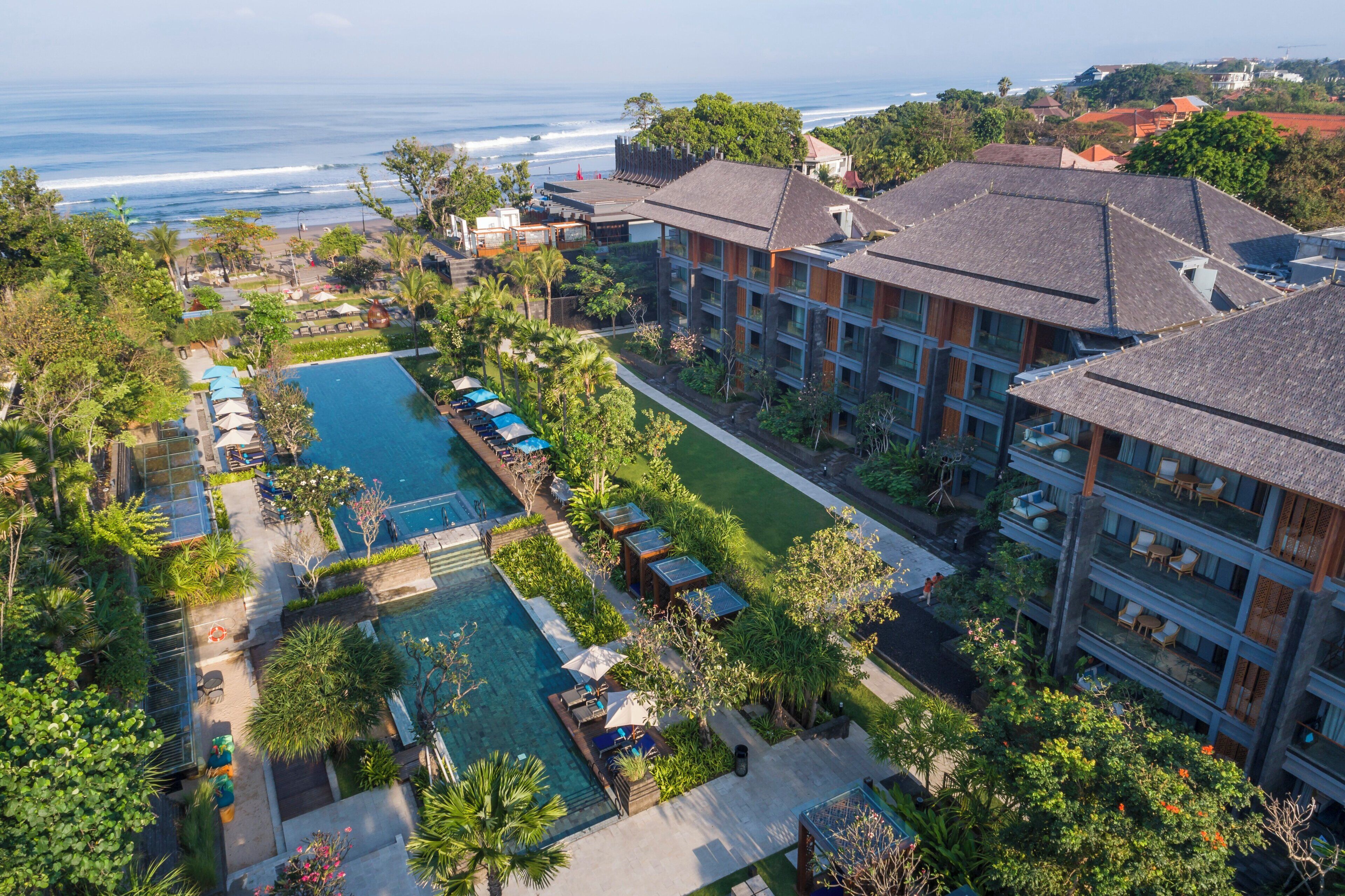 A resort with a large pool, multiple guest rooms, and a view of the ocean.