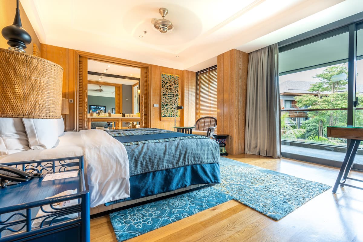 Ein modernes Hotelzimmer mit einem großen Bett, einem Schreibtisch, einem Stuhl und einem Balkon mit Blick ins Freie.
