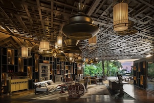 A spacious lounge area with multiple seating options, including sofas and chairs, and a variety of hanging light fixtures.