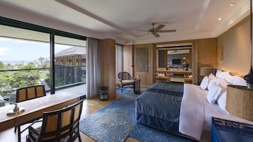 A hotel room with a large balcony, a bed with white linens, a desk with a lamp, and a chair.
