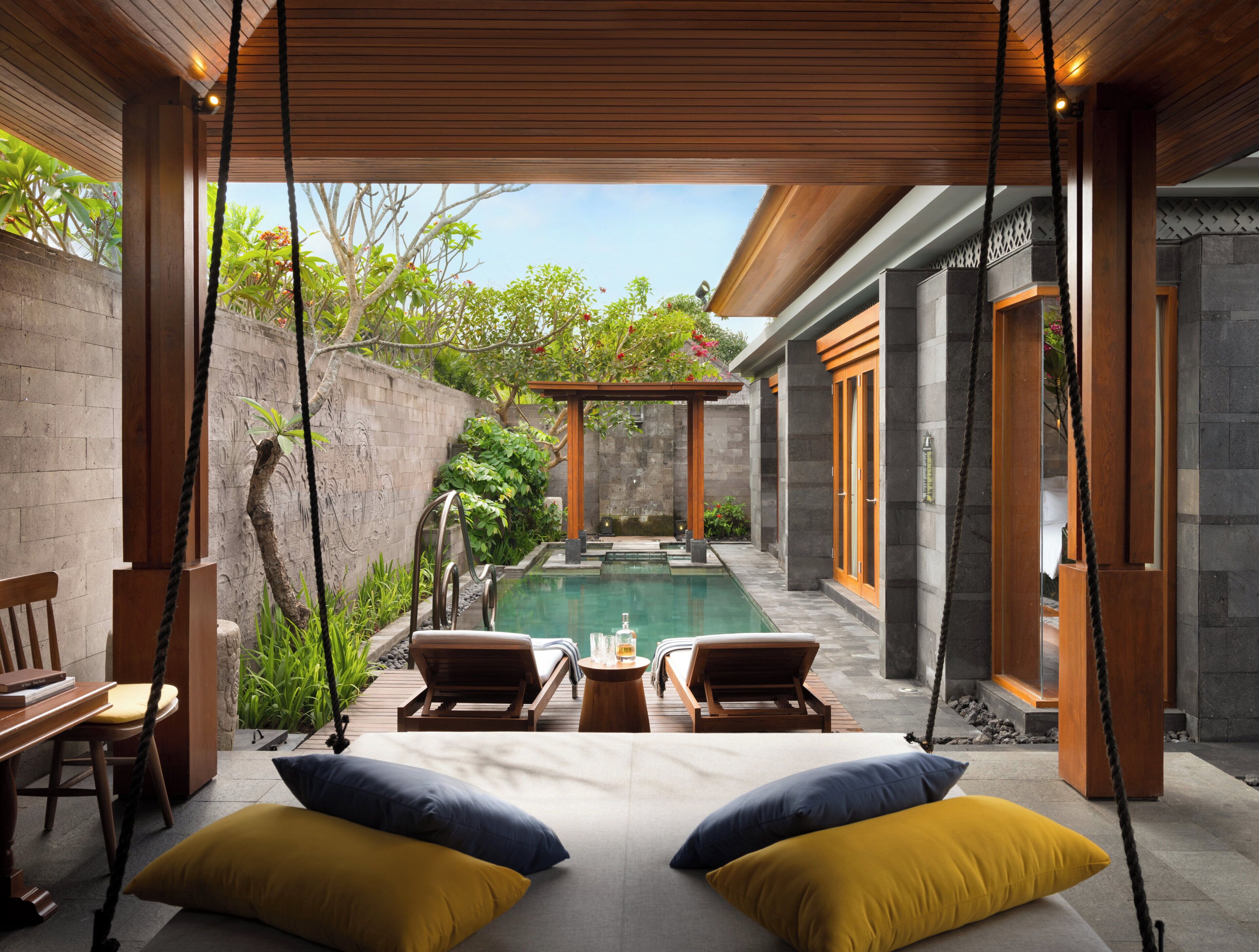 Uma área de relaxamento ao ar livre moderna, com balanço, assentos e piscina.