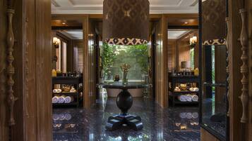A luxurious lobby with a marble floor, a central round table, and a large mirror.