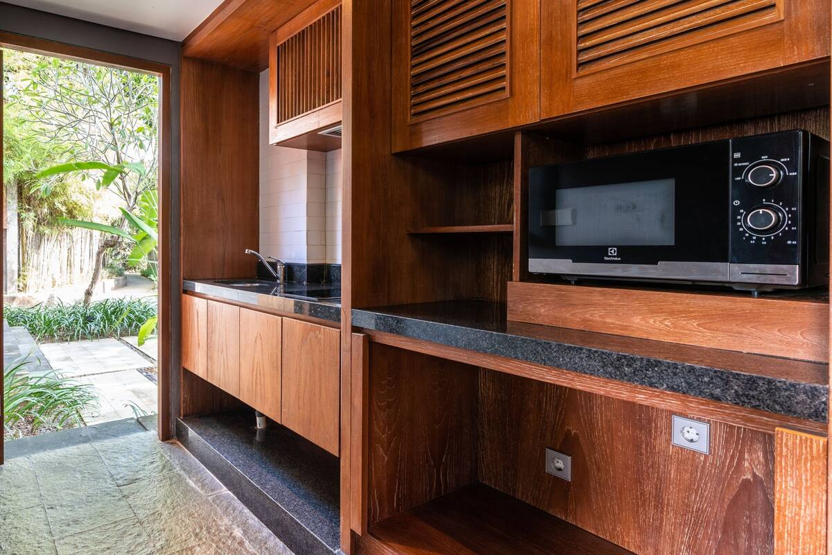 Eine moderne Küche mit Holzausstattung, einer integrierten Mikrowelle und einem Spülbecken.