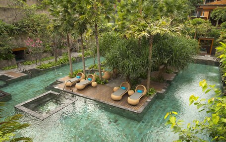 A serene indoor pool area with lounge chairs and lush greenery.