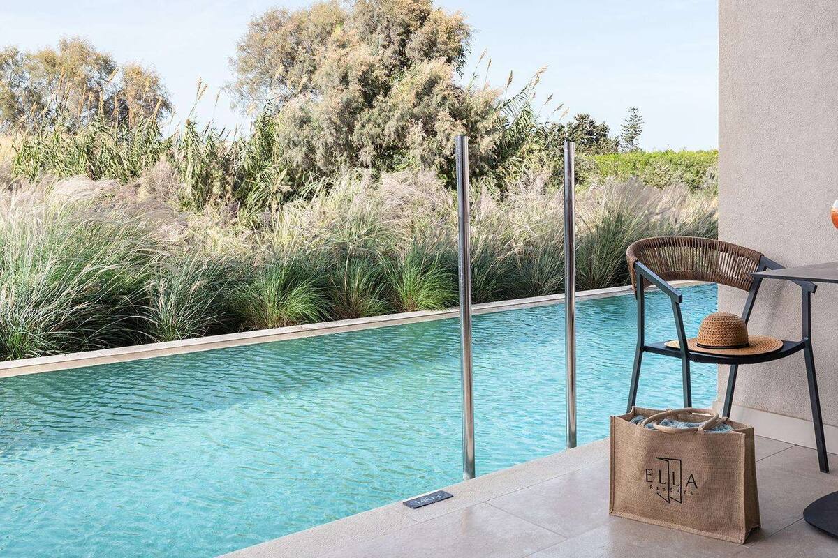 Un espace aménagé au bord de la piscine, avec une table, deux chaises, un verre et une petite plante.