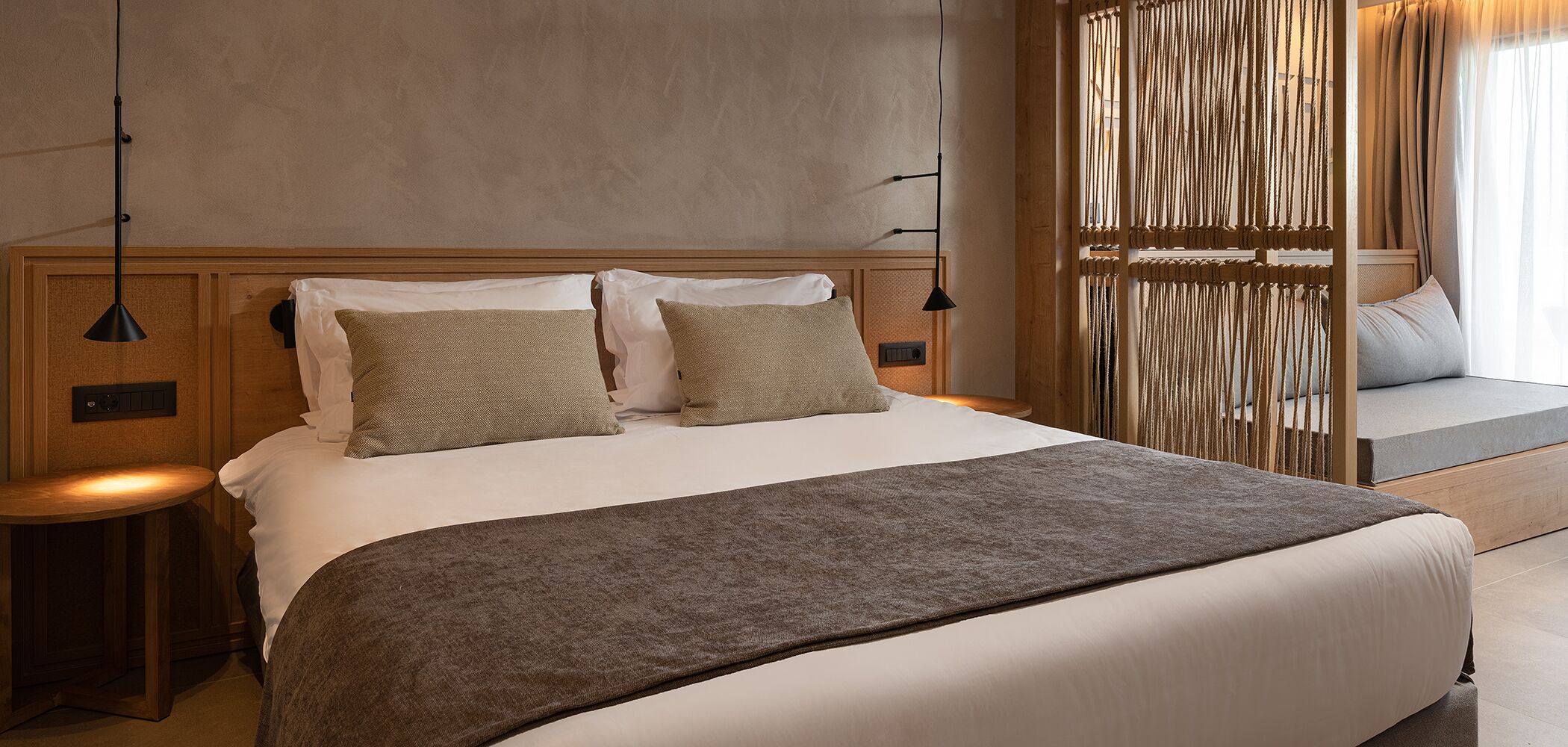Une chambre d’hôtel moderne avec un grand lit, deux tables de chevet, une tête de lit et un panneau décoratif mural.