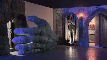 A large hand sculpture in a dimly lit room with stone walls and arched doorways.