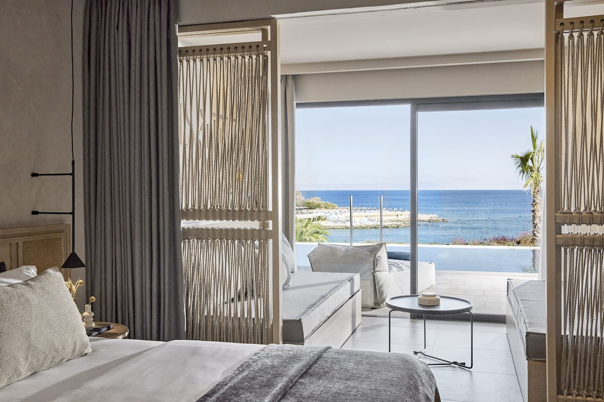 Une chambre d’hôtel avec un lit, un canapé, une petite table et une vue sur l’océan.