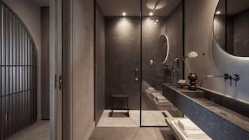 Ein modernes Badezimmer mit einer in Glas eingeschlossenen Dusche, einem großen Spiegel und einem Waschtisch mit Marmorplatte.