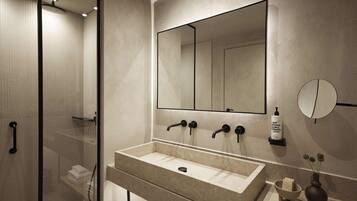 A modern bathroom with a large mirror, a beige sink, and a glass-enclosed shower.