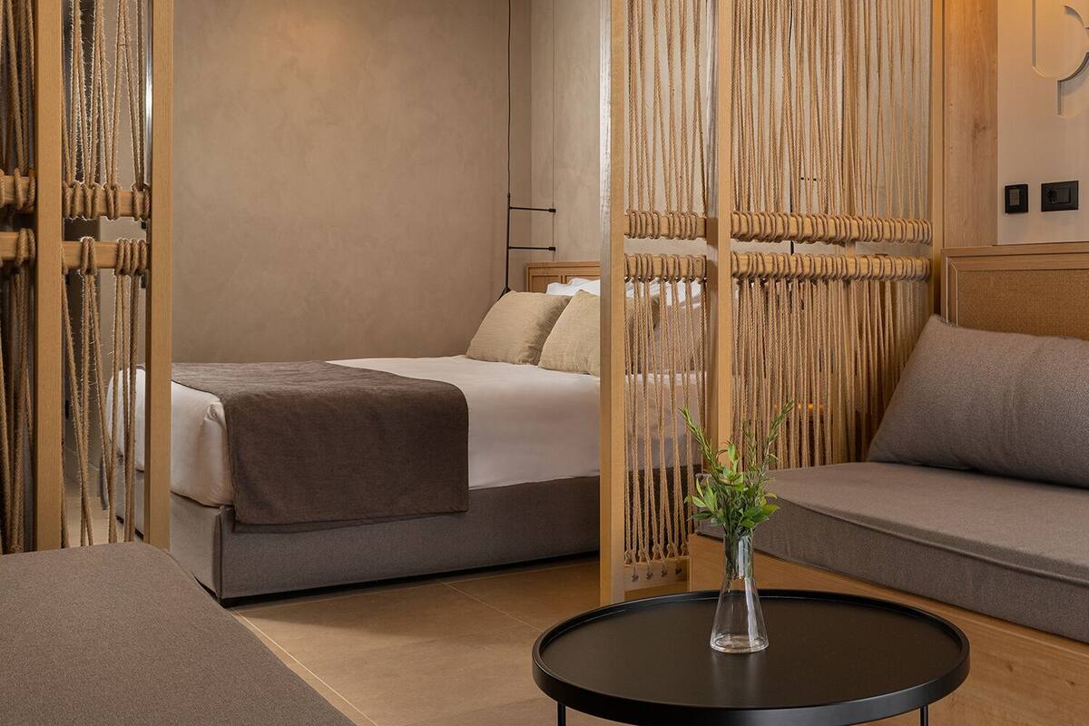 Une chambre d’hôtel moderne avec un lit, un canapé et une petite table sur laquelle est posé un vase.