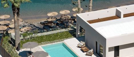 Un hotel moderno con piscina, tumbonas y sombrillas.