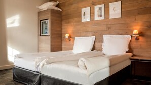 A neatly made bed with white linens, a wooden headboard, and two wall-mounted lamps. - Hotel La Rochette (Labaroche)