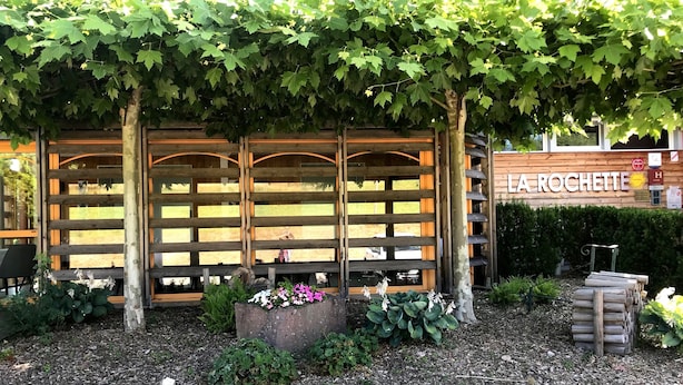 A wooden pergola with climbing vines, a sign reading "LA ROCHETTE", and a garden with various plants and flowers. - Hotel La Rochette (Labaroche)