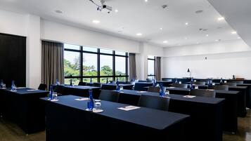 A conference room with multiple tables, chairs, and a projector screen.
