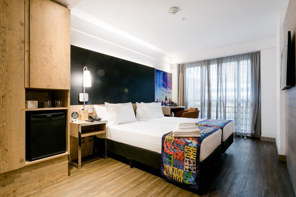 Una habitación de hotel con cama, mesita de noche, escritorio y televisor.