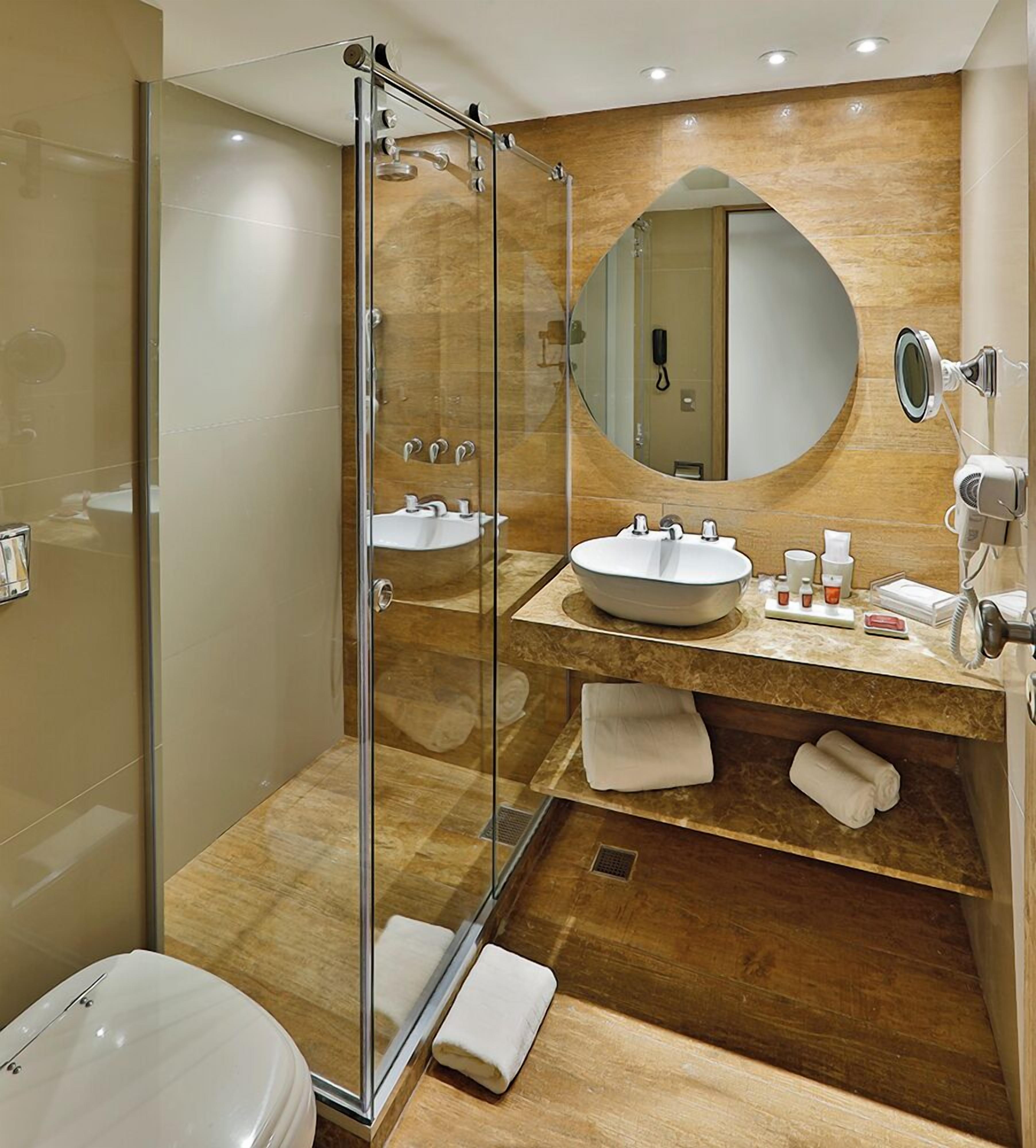 A modern bathroom with a glass-enclosed shower, two sinks, a large mirror, and a towel rack.