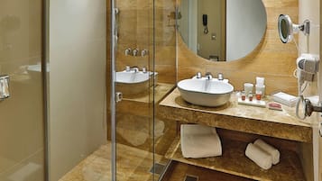 A modern bathroom with a glass-enclosed shower, two sinks, a large mirror, and a towel rack.