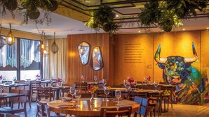 Un restaurant avec des tables et des chaises en bois, ainsi que des plantes suspendues.