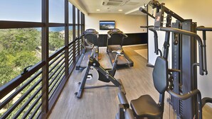 Une salle de sport équipée de tapis de course, d’un rameur et d’un banc de musculation.