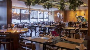 A restaurant with multiple dining tables, chairs, and hanging plants.