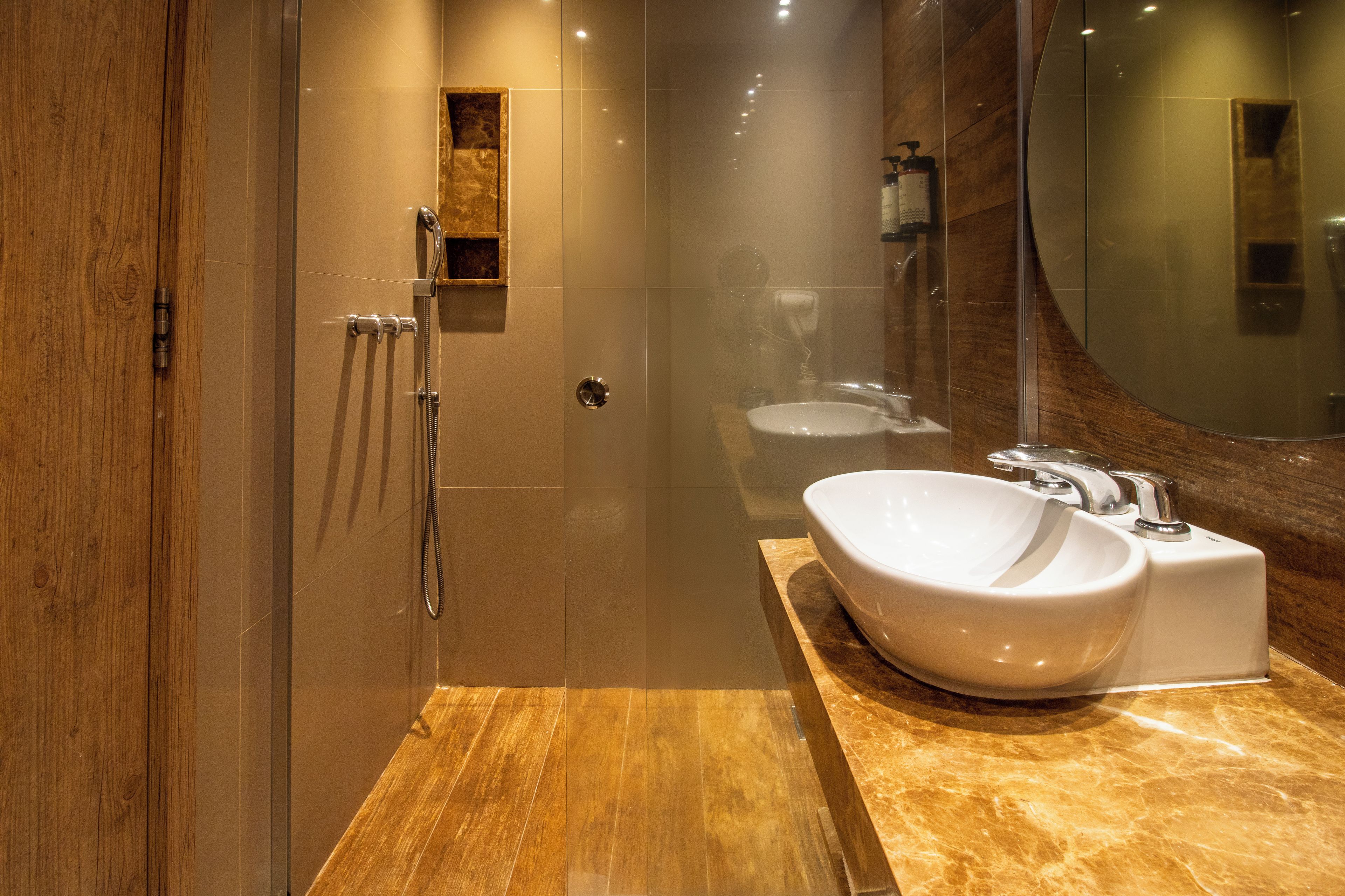 A modern bathroom with a glass-enclosed shower, a marble countertop, and a large mirror.