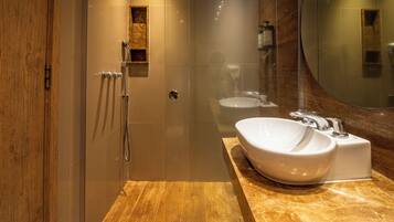 A modern bathroom with a glass-enclosed shower, a marble countertop, and a large mirror.